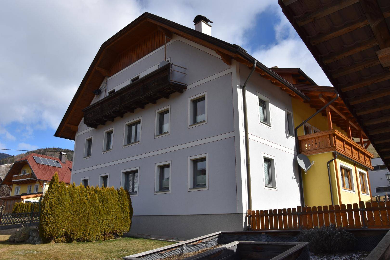 Rückansicht des Hauses mit Balkonen, Holzverkleidung und gepflegtem Gartenbereich.