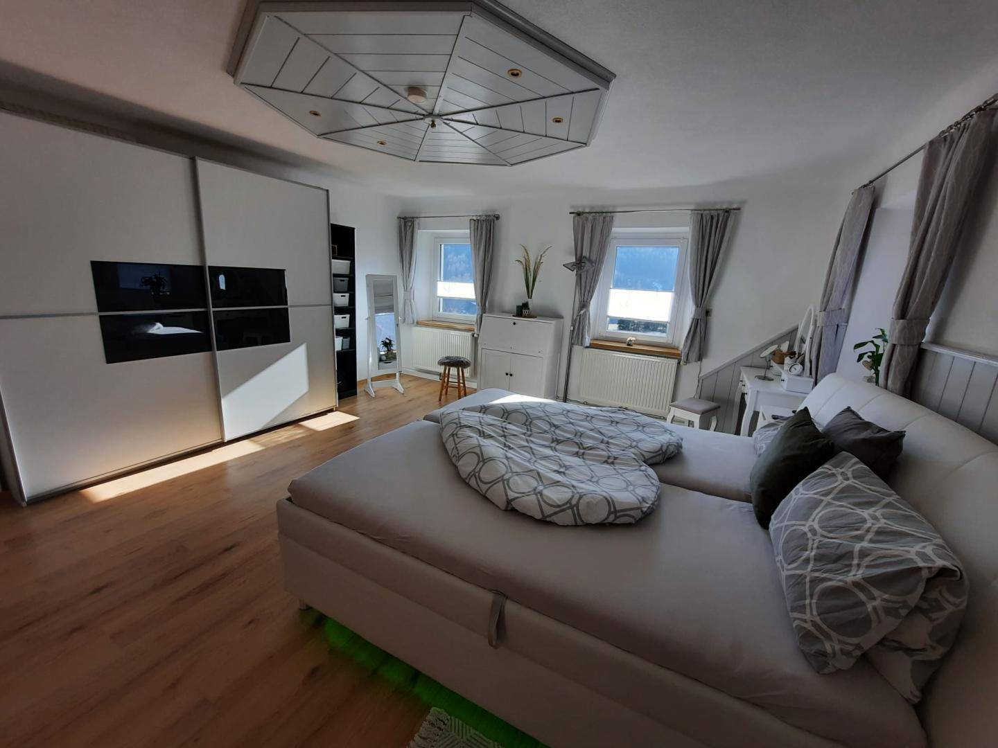 Schlafzimmer mit Doppelbett, großem Kleiderschrank und Laminatboden.