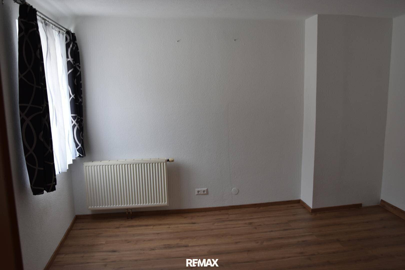 Leerer Raum mit Laminatboden und einem Fenster, bereit zur individuellen Einrichtung.