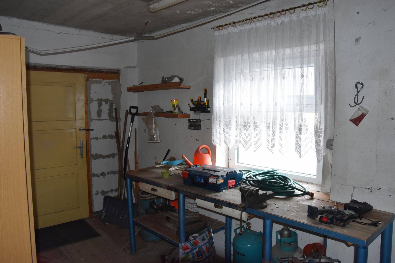 Werkstattraum mit Arbeitstisch, Werkzeugen und einem Fenster für Tageslicht.