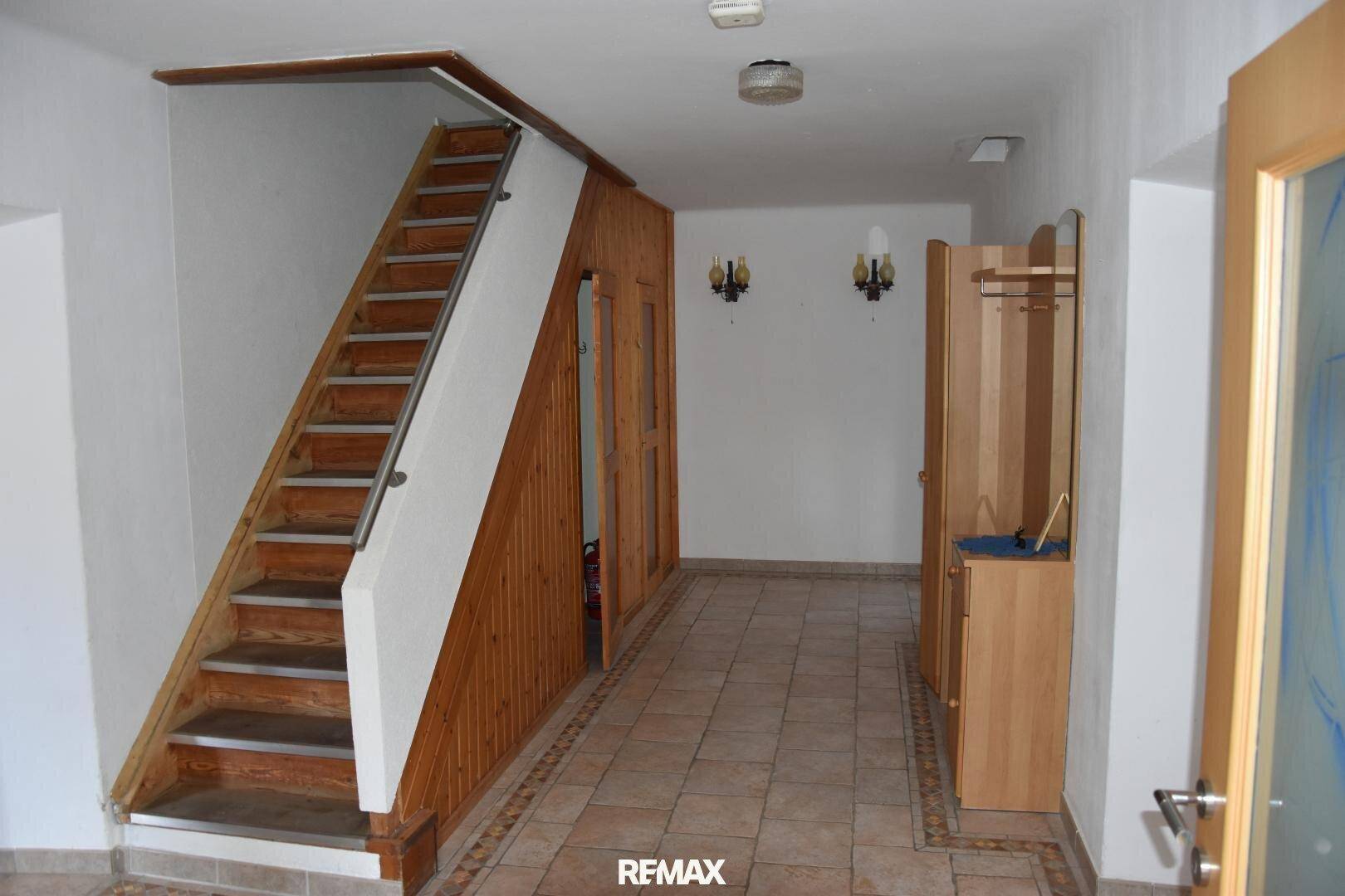 Geräumiger Flur mit Holztreppe, gefliestem Boden und traditioneller Wandverkleidung.