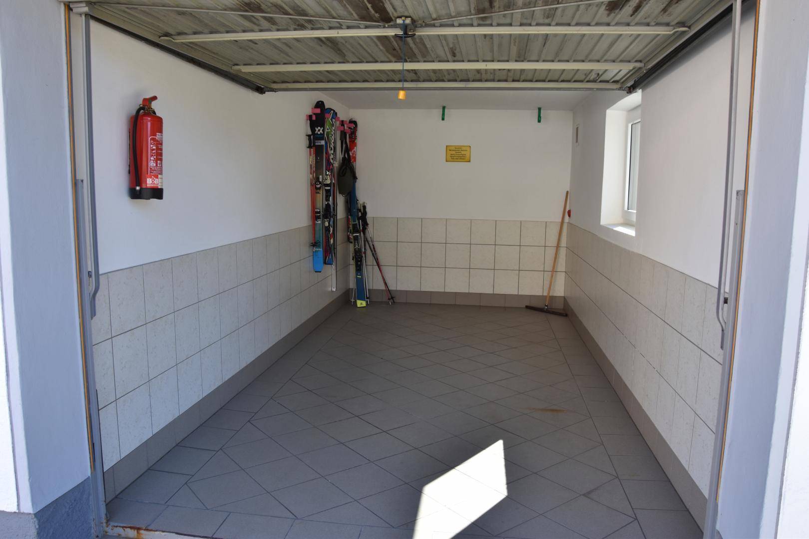 Geräumige Garage mit Fliesenboden und Platz für ein Fahrzeug.