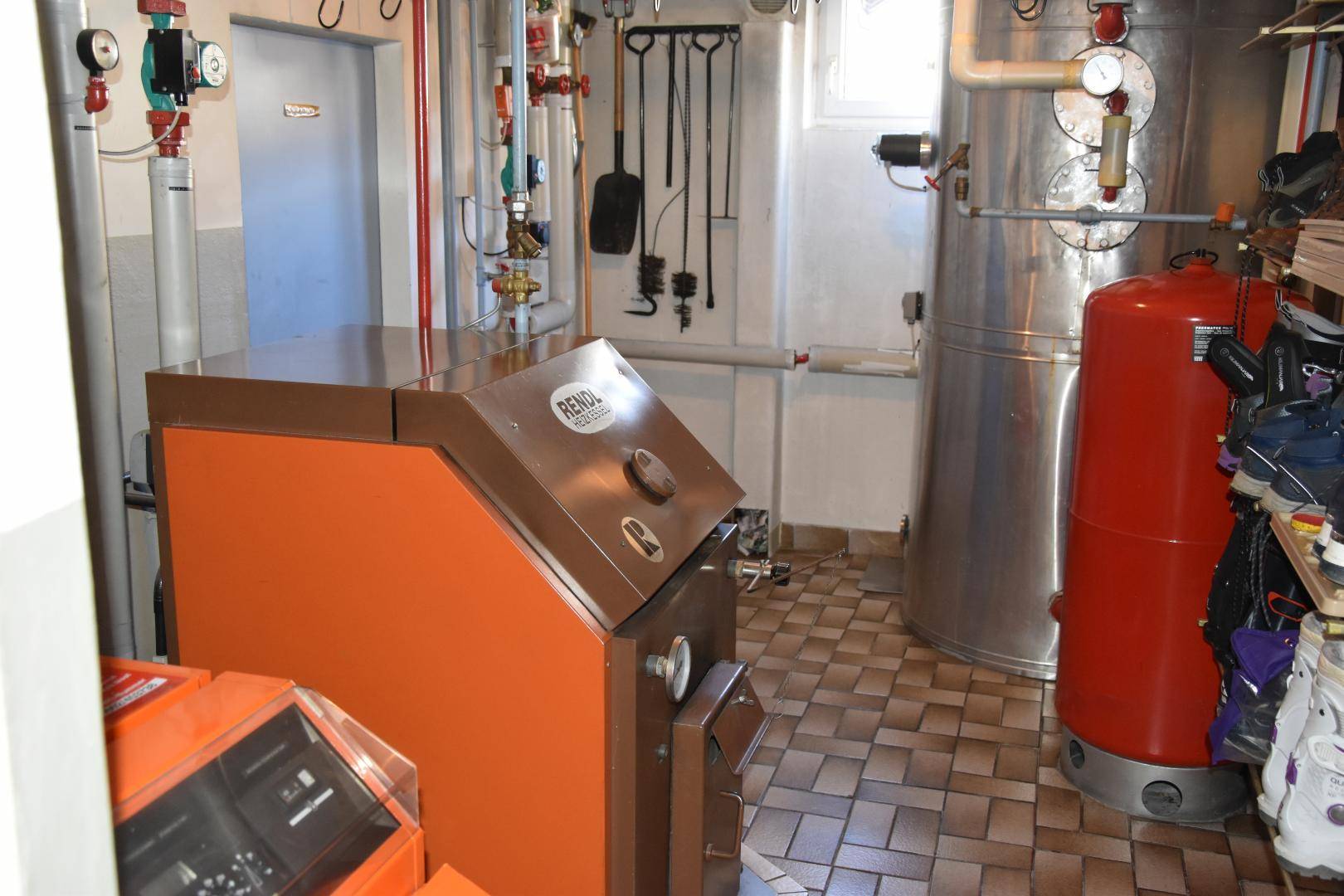 Heizungsraum mit großem Kessel und Warmwasserspeicher, ausgestattet mit Fliesenboden.