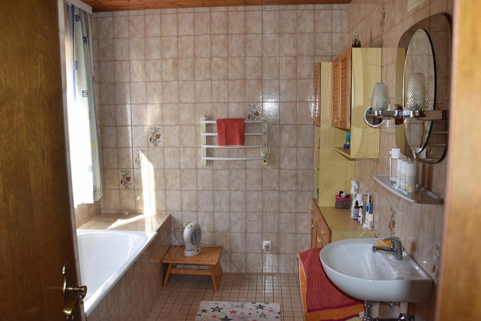Gefliestes Badezimmer mit Badewanne, Duschbereich und Einzelwaschbecken.