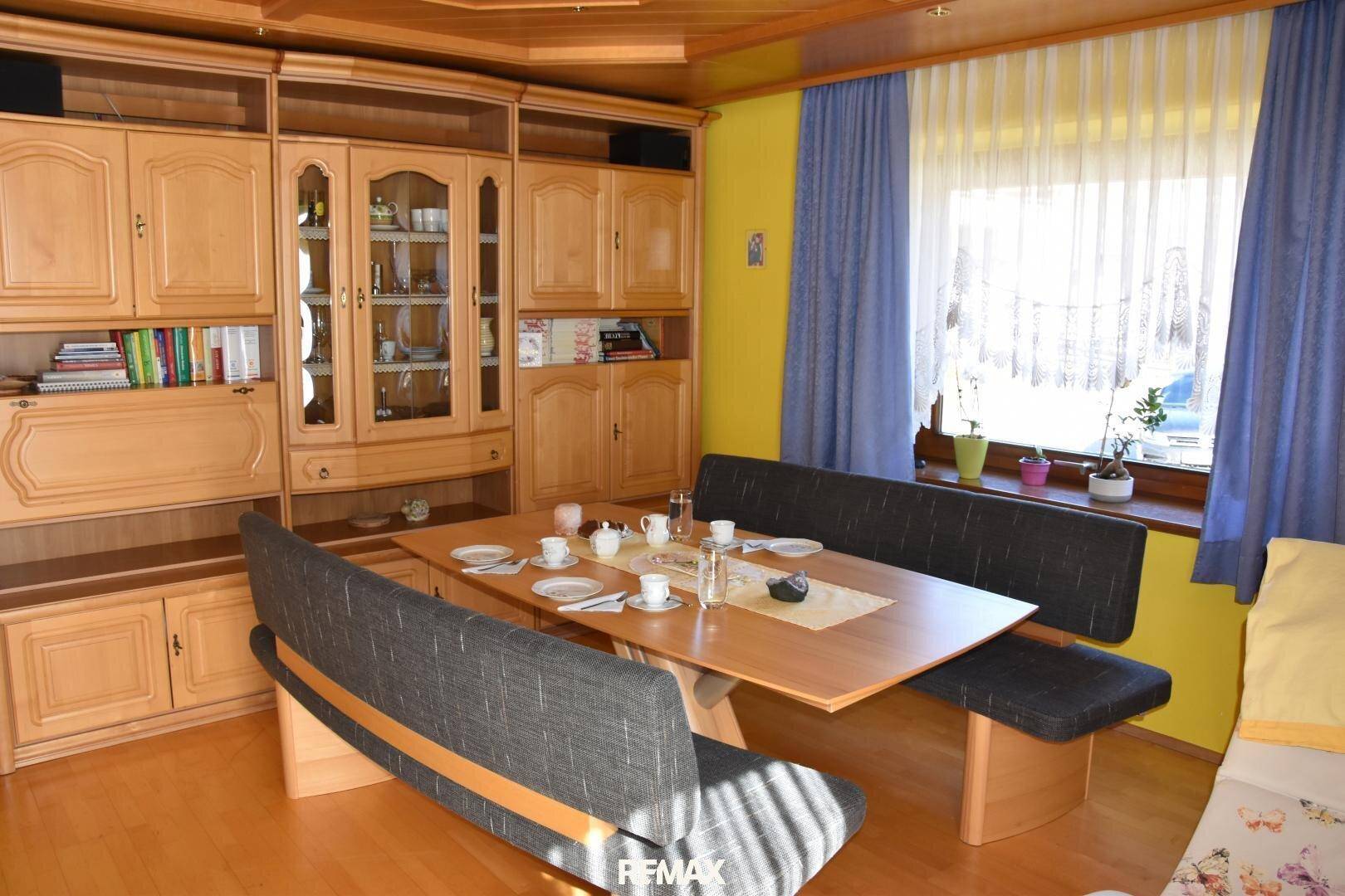 Geräumiger Wohn-Essbereich mit Holzmöbeln, Esstisch und großem Fenster.