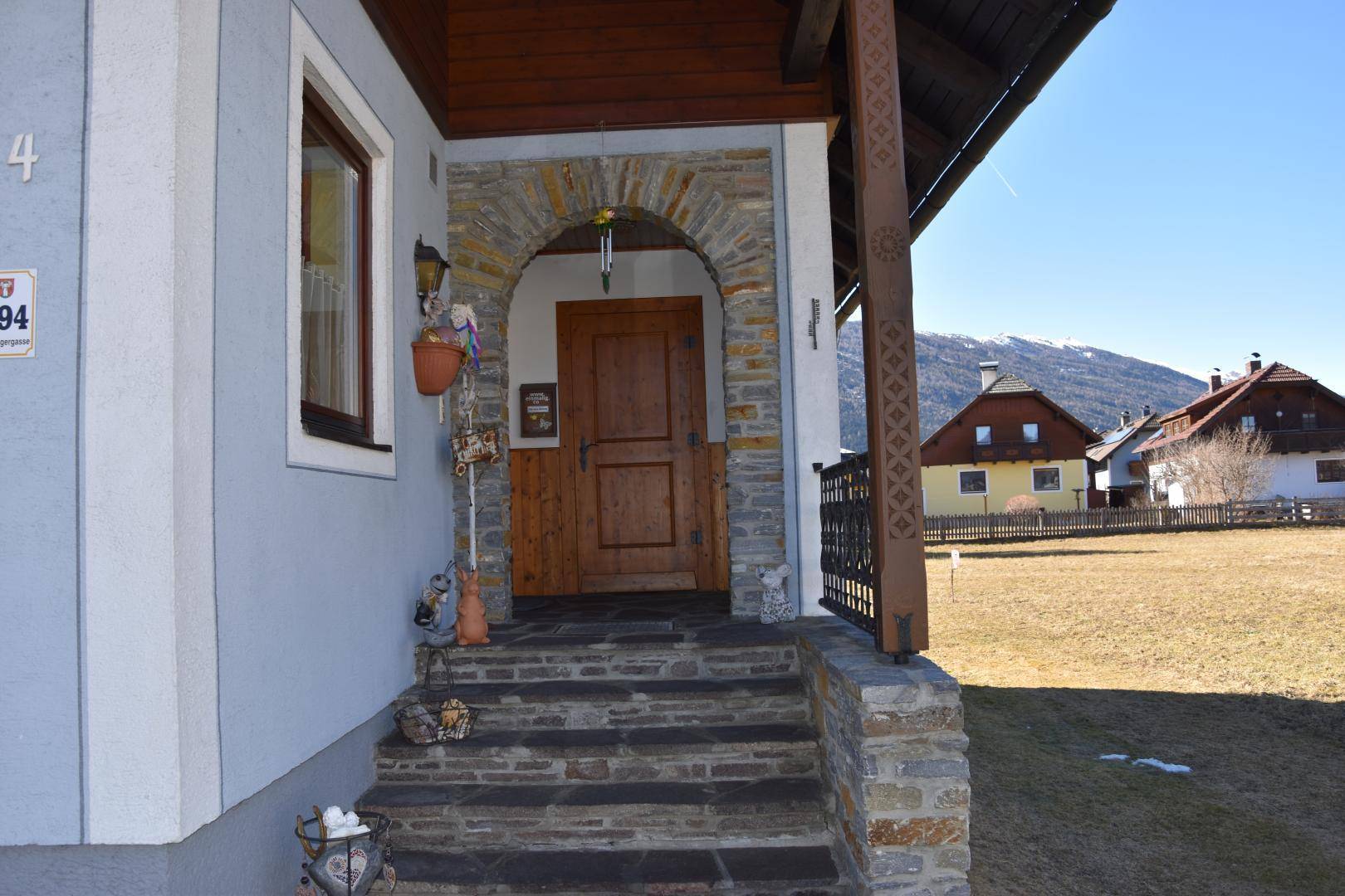 Eingangsbereich des Hauses mit Steintreppe, Holztür und rustikalem Steinbogen.
