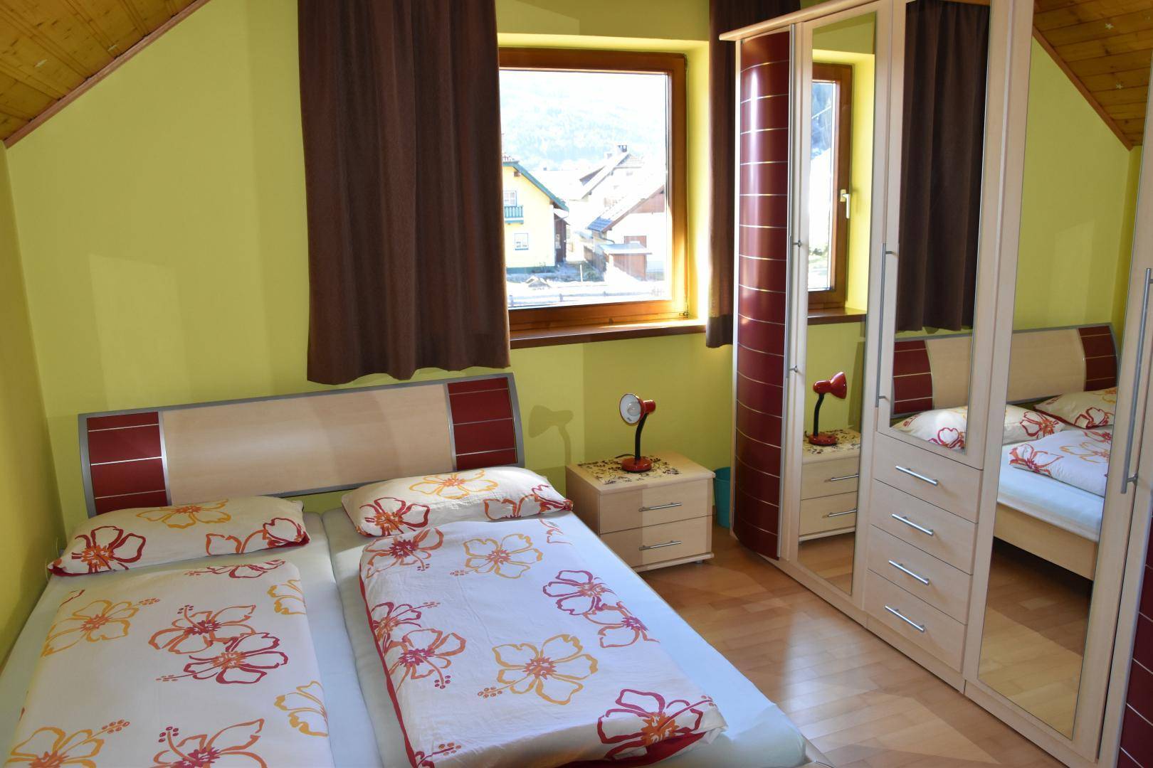 Schlafzimmer im Dachgeschoss mit zwei Einzelbetten, Spiegelschrank und grünlicher Wandfarbe.