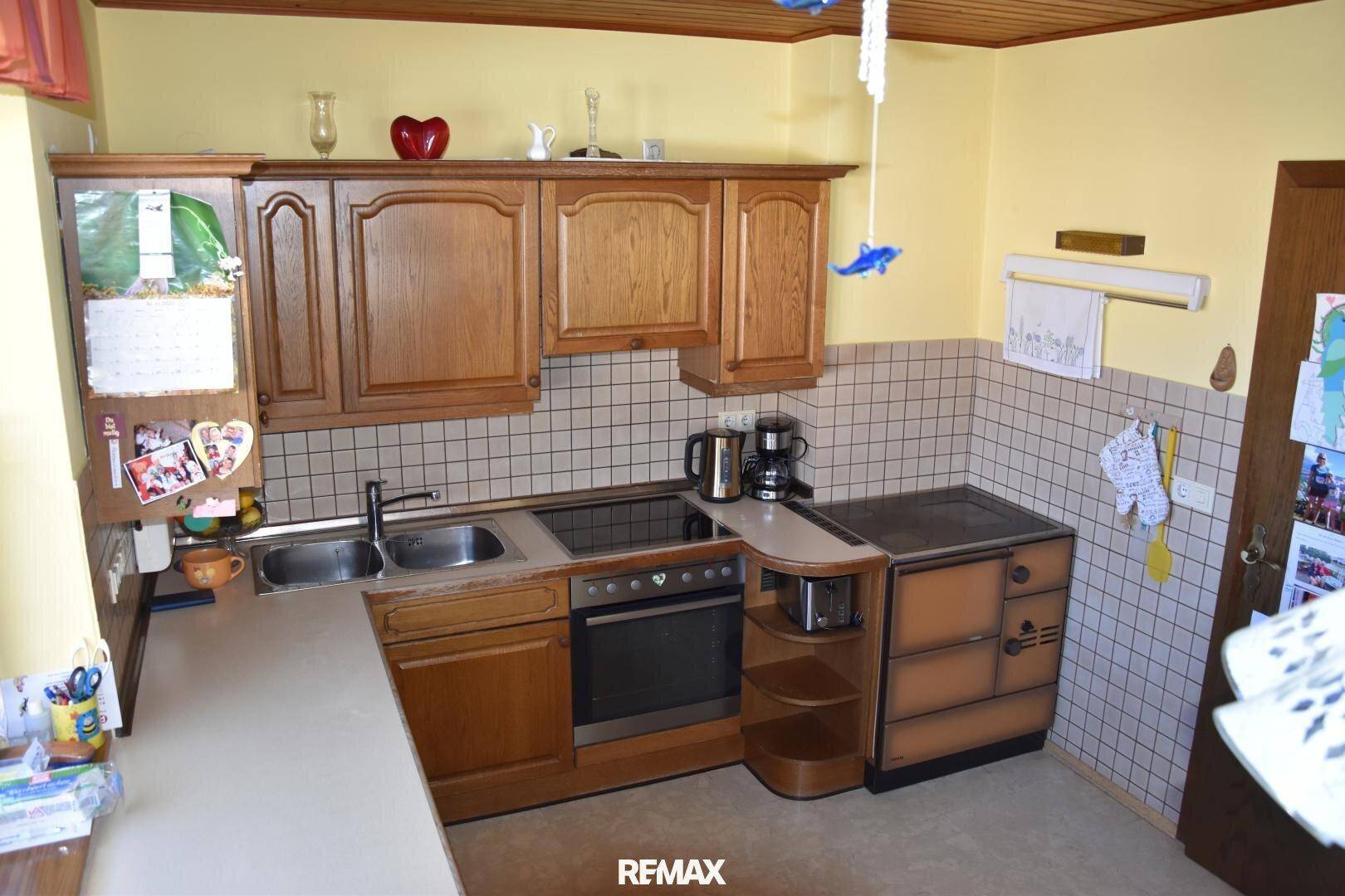 Traditionelle Küche mit Holzschränken, Fliesenrückwand und integrierten Geräten.