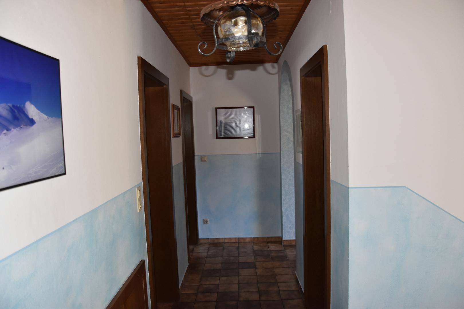Flur mit Holzdecke, hellblauen Wänden und braunen Türen.