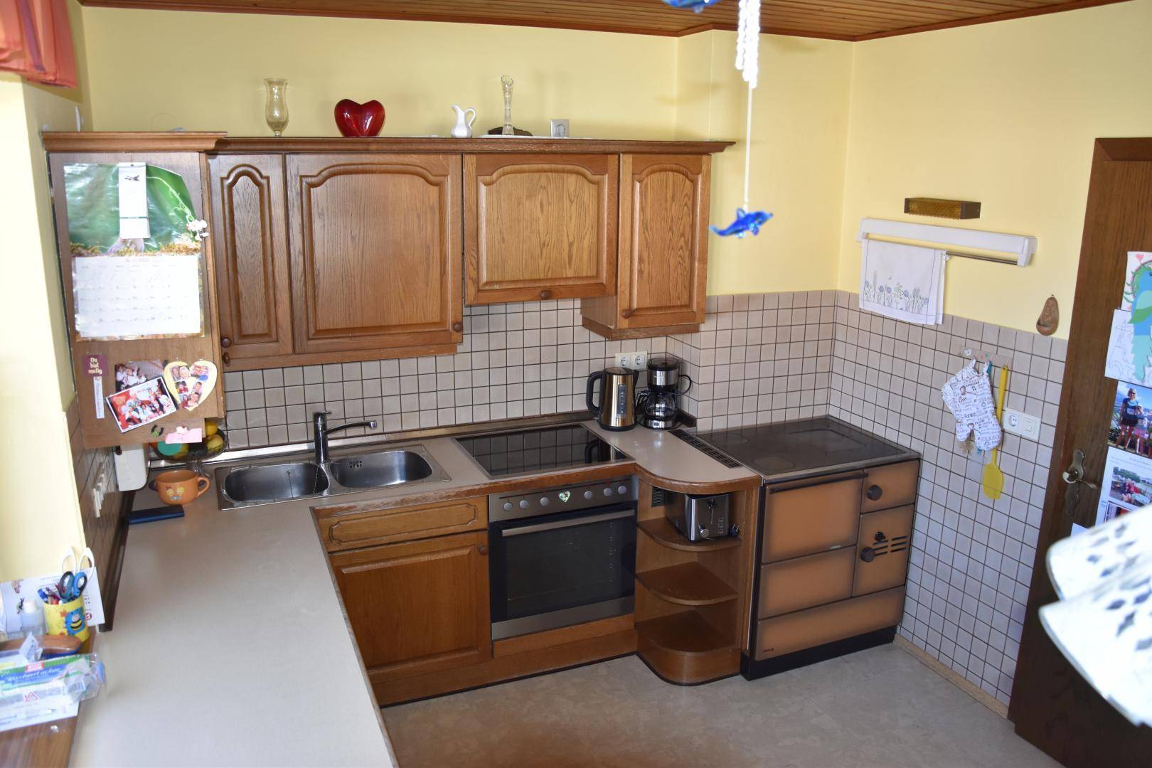 Traditionelle Küche mit Holzschränken, beiger Arbeitsplatte und Induktionskochfeld.