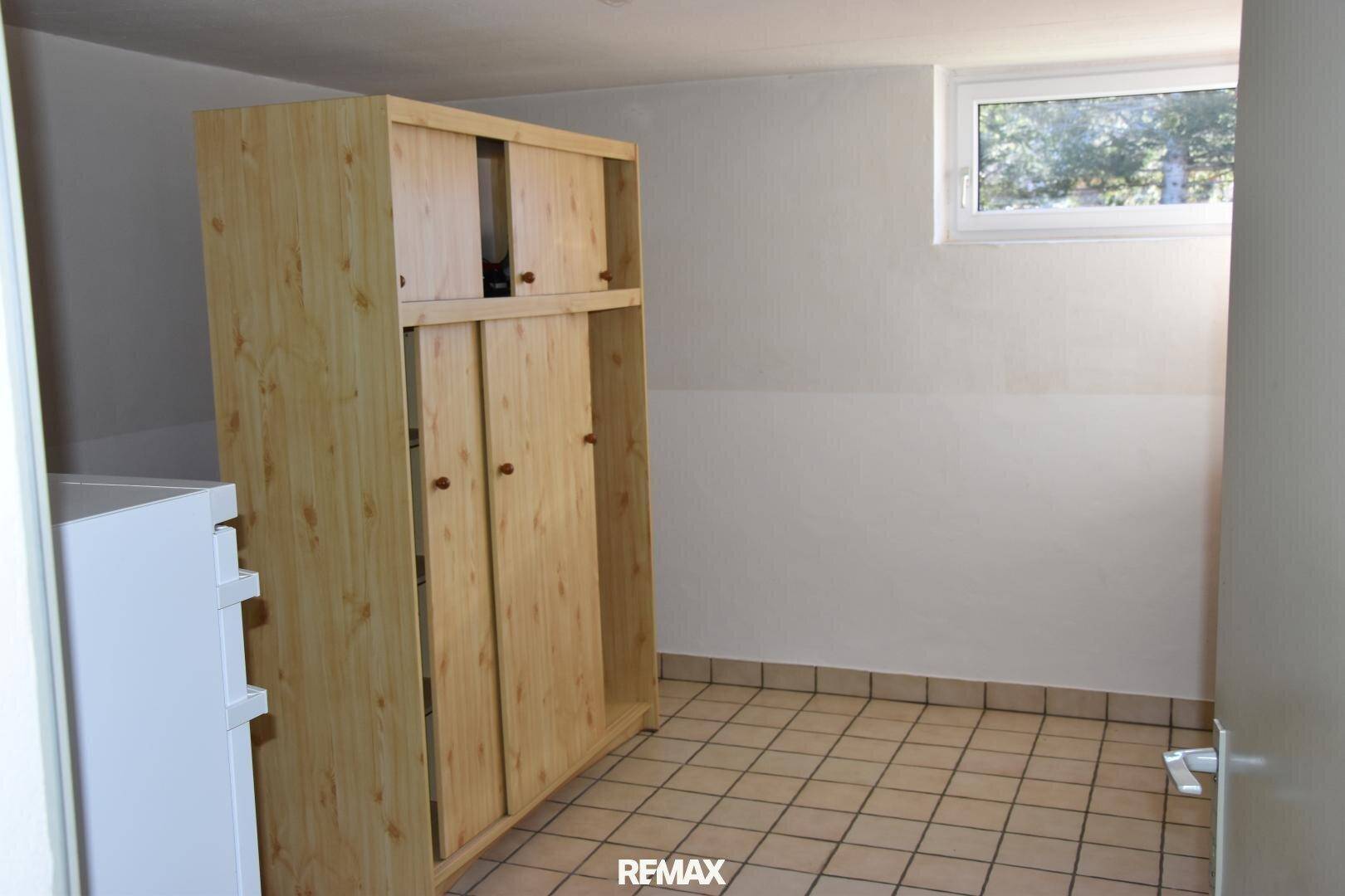 Abstellraum mit Holzschrank und Fliesenboden, ideal für zusätzlichen Stauraum.