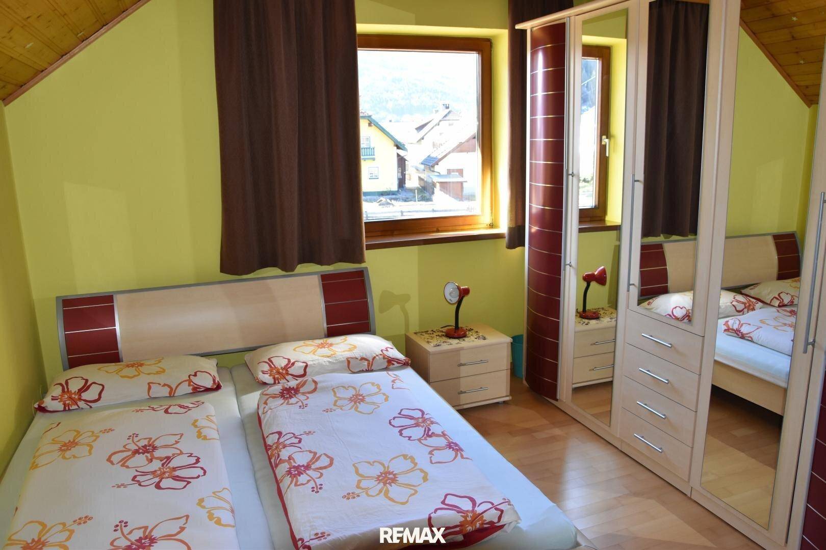 Helles Schlafzimmer mit zwei Einzelbetten, Spiegelschrank und Blick auf die Umgebung.