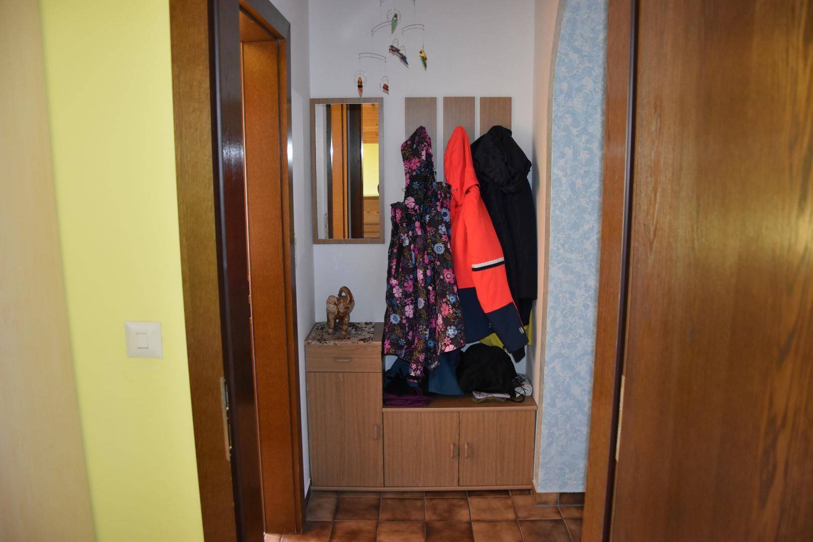Eingangsbereich mit Garderobe, Spiegel und gefliestem Boden.