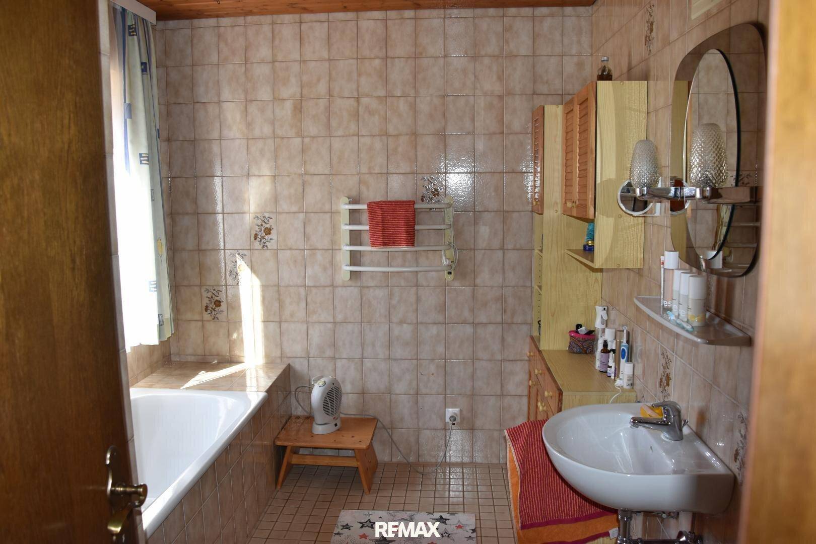 Badezimmer mit Badewanne, Fliesenboden und Holzdecke in traditionellem Stil.