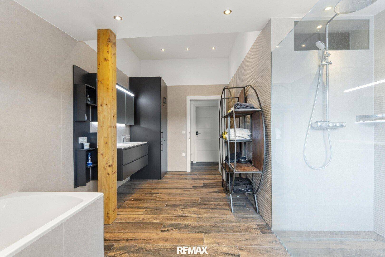 Modernes Badezimmer mit begehbarer Dusche, Badewanne und dunklen Möbeln.
