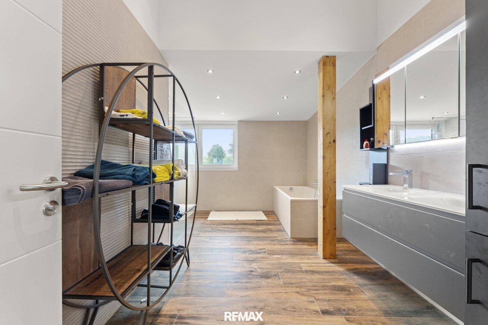 Geräumiges Badezimmer mit Badewanne, großem Waschtisch und Fenster für Tageslicht.