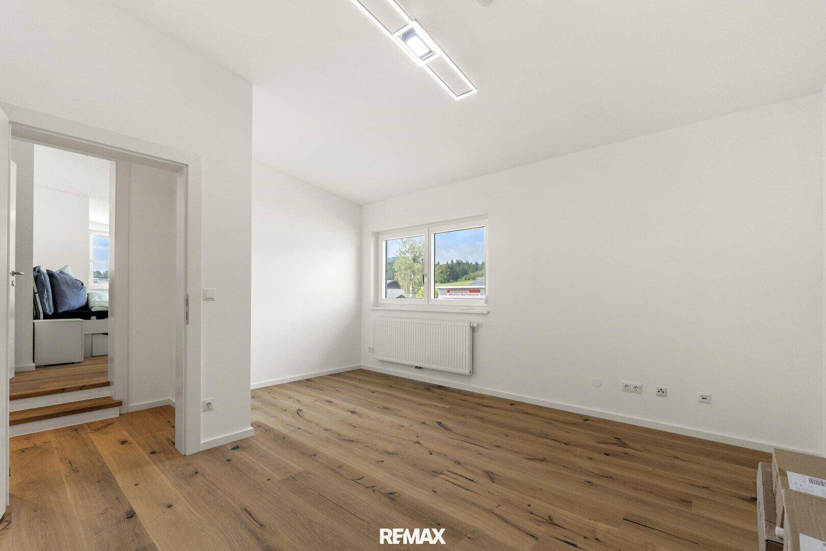 Helles, leeres Zimmer mit Holzboden und Fenster, ideal als Schlaf- oder Kinderzimmer.