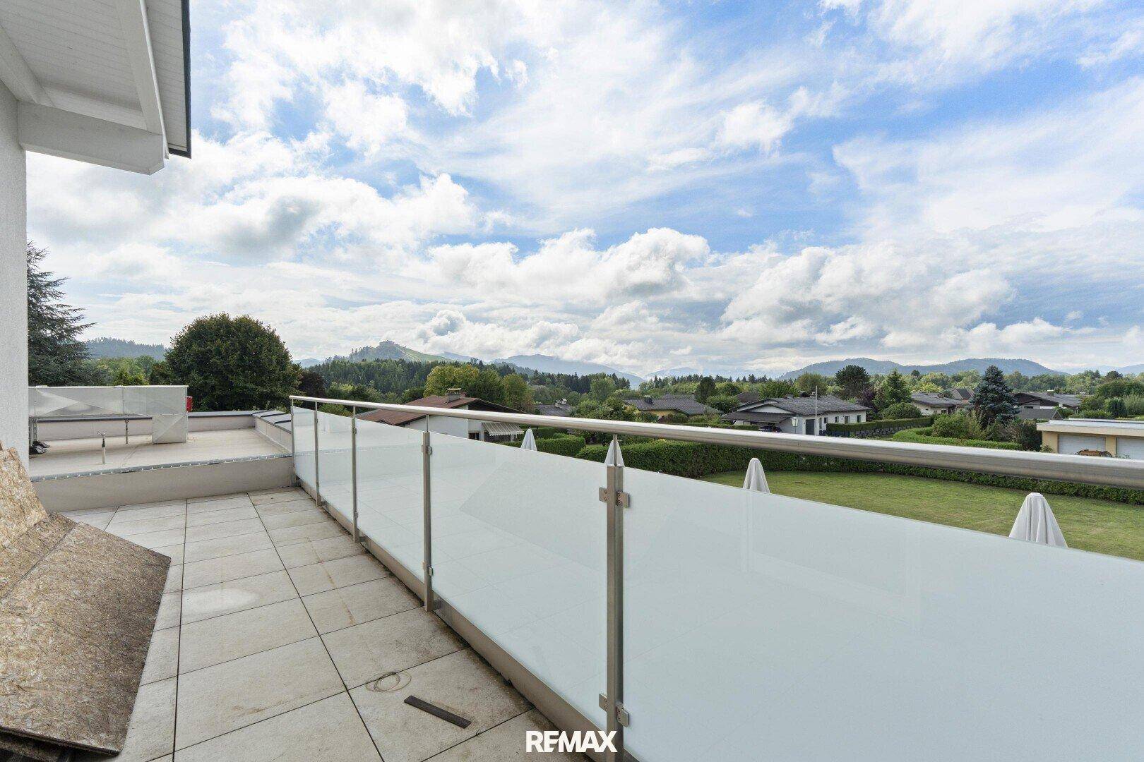 Geräumige Terrasse mit Glasgeländer und Panoramablick auf die umliegende Berglandschaft.