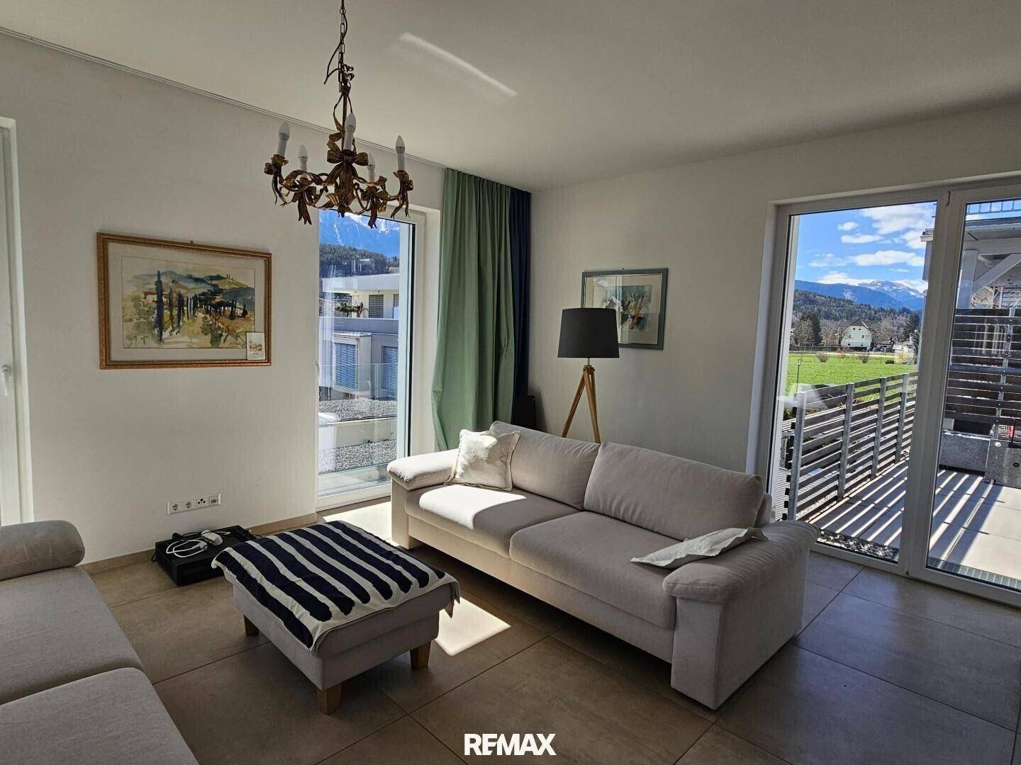 Lichtdurchflutetes Wohnzimmer mit bequemen Sofas, großen Fenstern und Zugang zur Terrasse.
