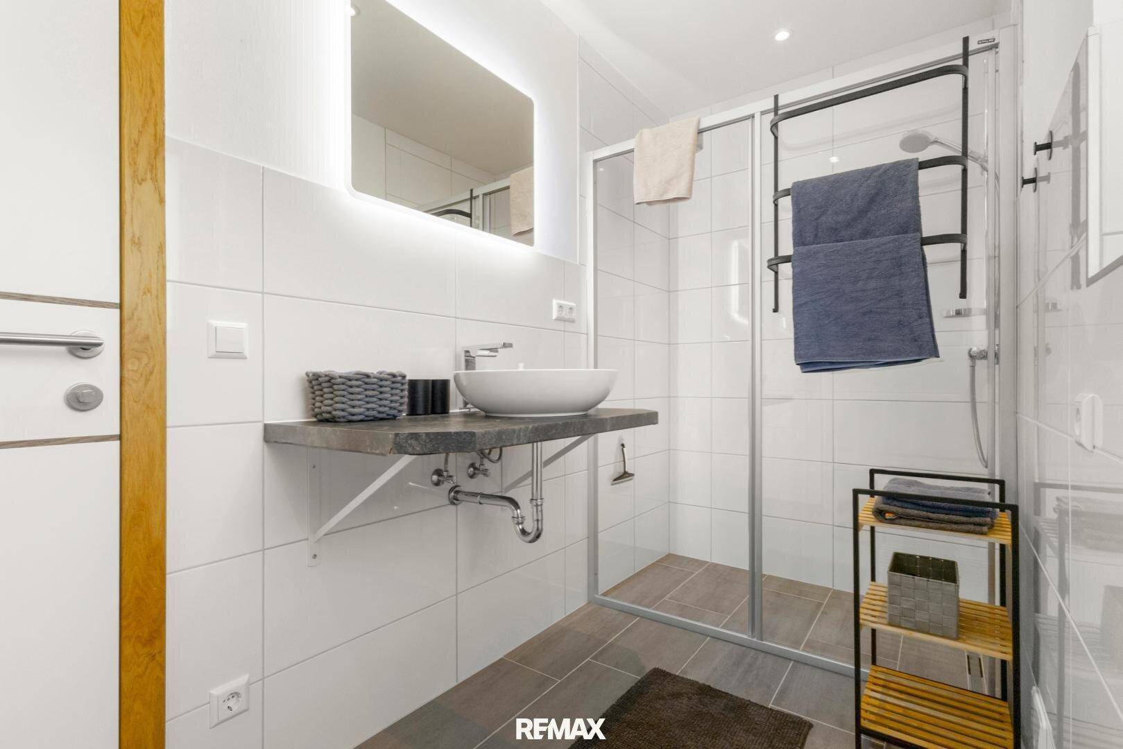 Helles, modernes Badezimmer mit ebenerdiger Dusche, Aufsatzwaschbecken und Handtuchhalter.
