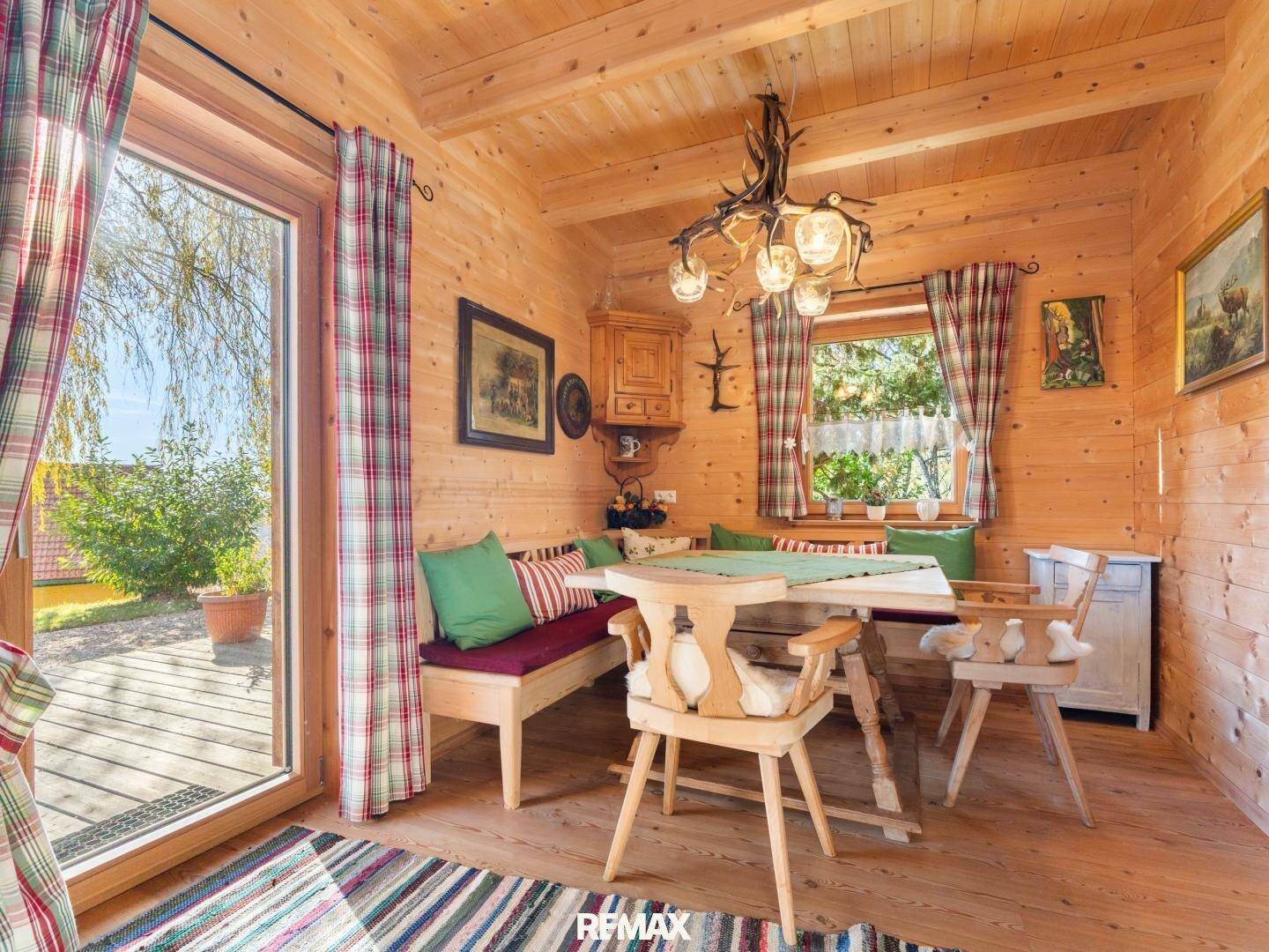 Heller Essbereich in einem Holzhaus mit traditionellen Möbeln und Zugang zur Terrasse.