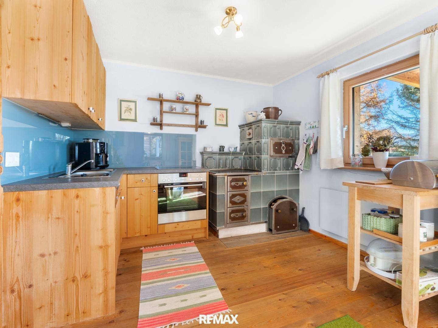 Rustikale Küche mit Holzelementen, blauem Fliesenspiegel und traditionellem Kachelofen.