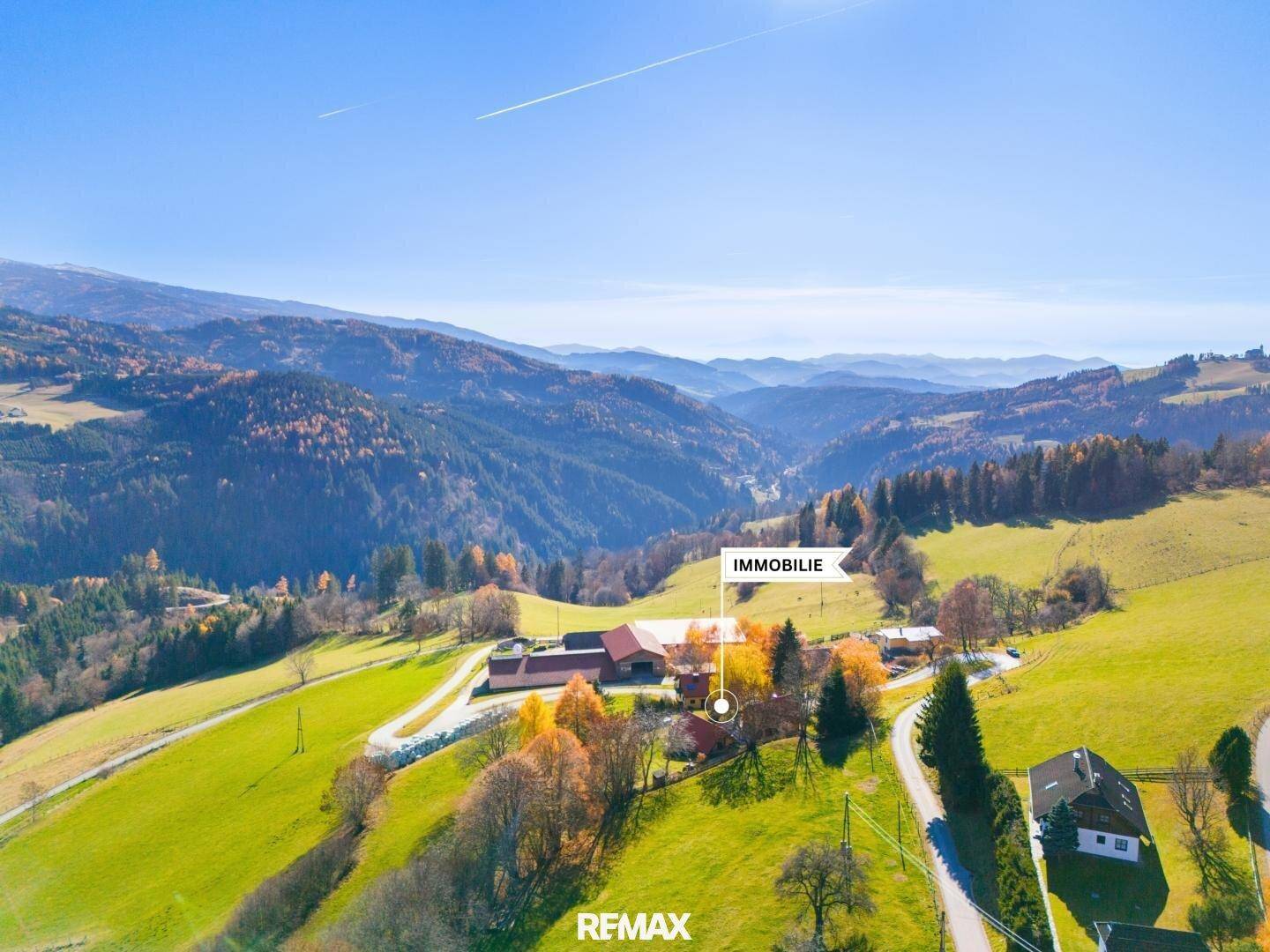 Luftaufnahme der Immobilie eingebettet in eine malerische Berglandschaft mit grünen Hügeln.