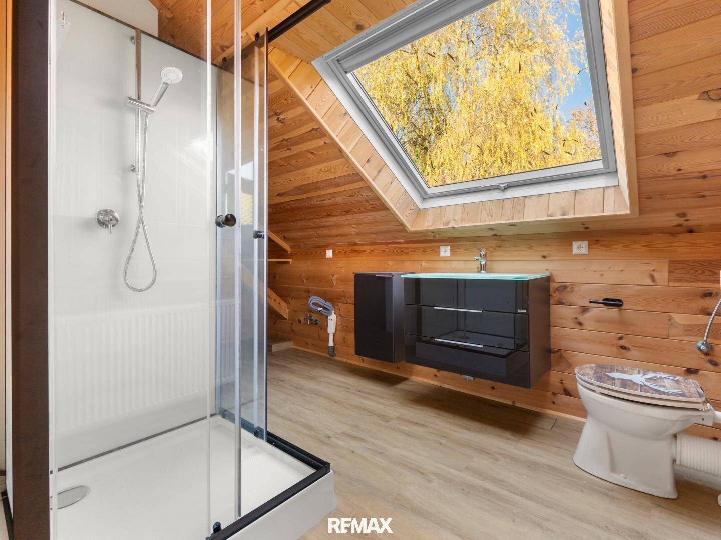 Modernes Badezimmer im Dachgeschoss mit Holzverkleidung, Dusche, Waschtisch und Dachfenster.
