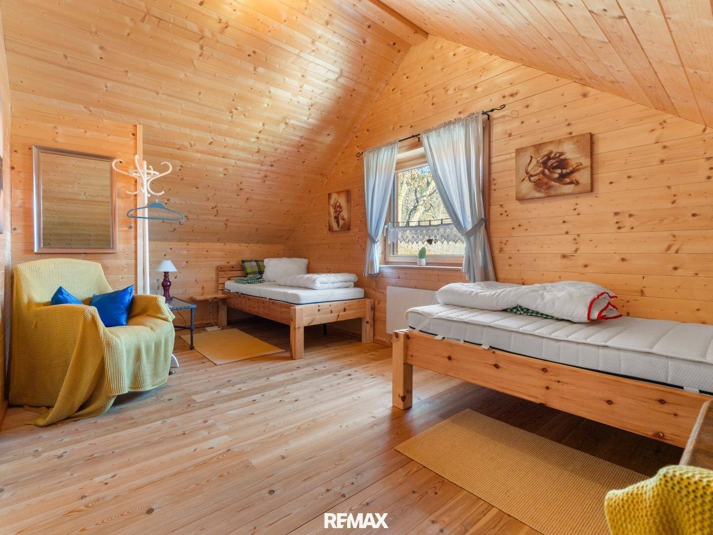 Gemütliches Schlafzimmer im Dachgeschoss mit Holzverkleidung, zwei Einzelbetten und Fenster.