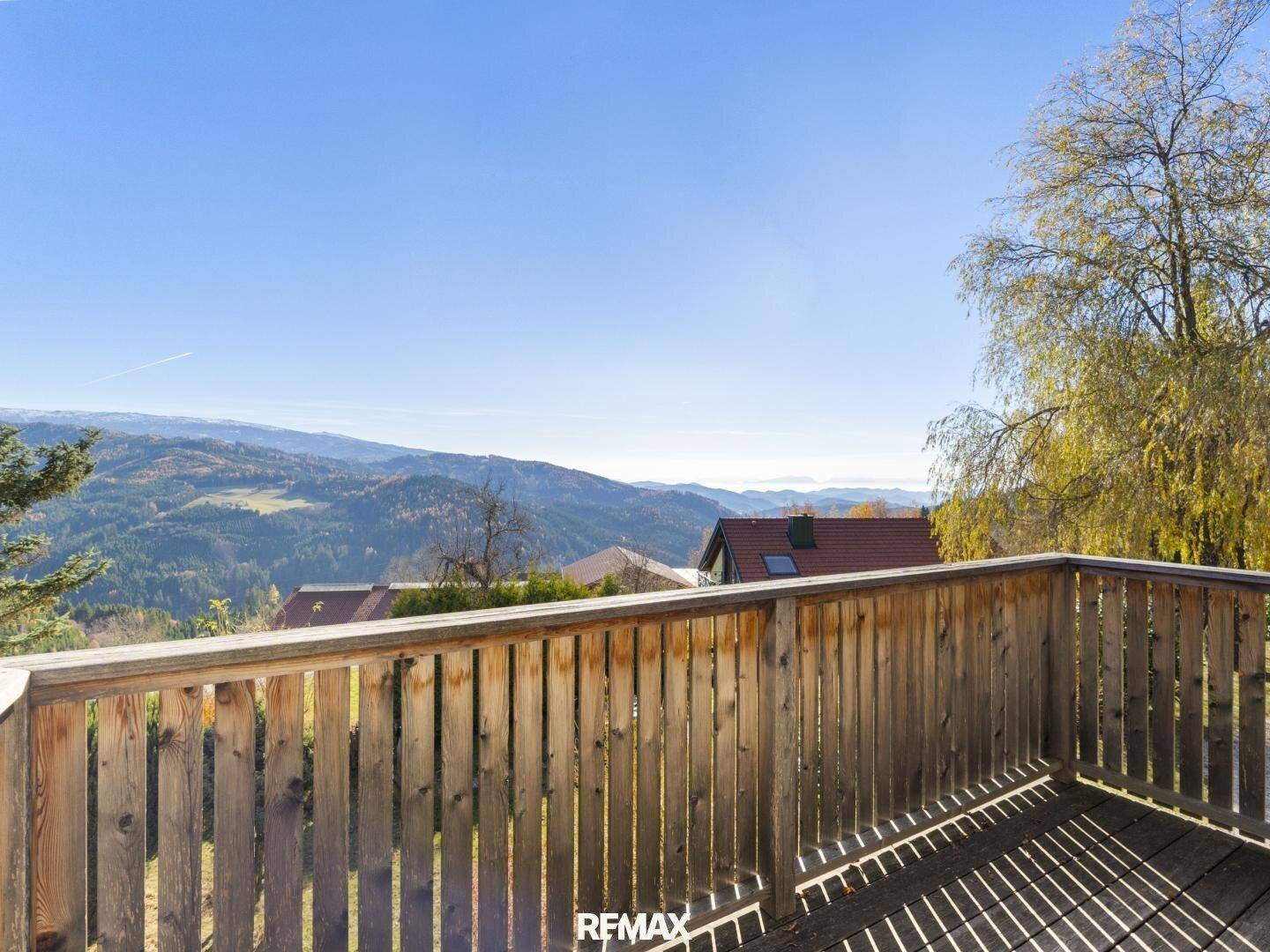 Geräumiger Holzbalkon mit Panoramablick auf die umliegende Berg- und Hügellandschaft.