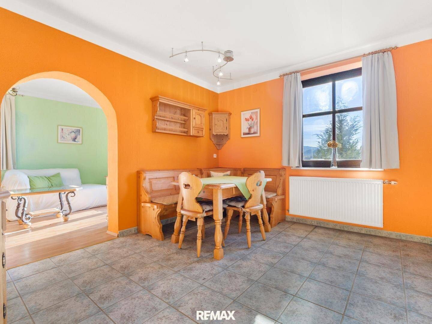Gemütlicher Essbereich mit orangefarbenen Wänden, traditionellen Holzmöbeln und Bergblick.