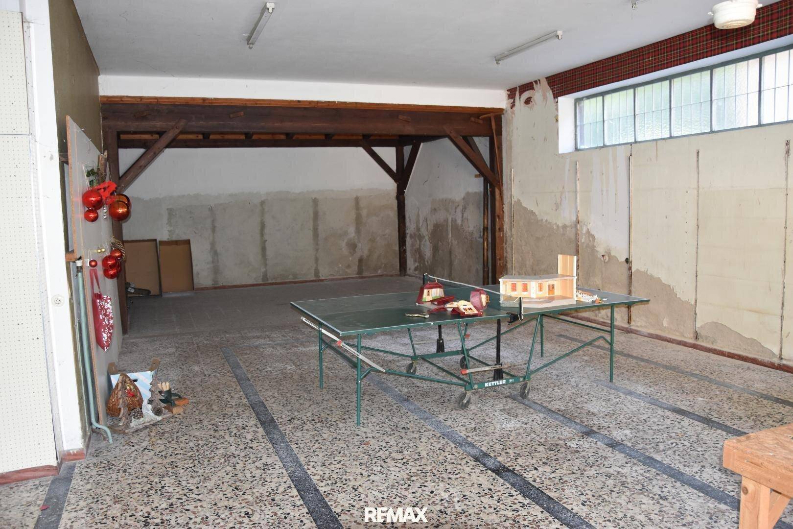 Großer, unfertiger Raum im Untergeschoss mit Tischtennisplatte und sichtbaren Holzbalken.