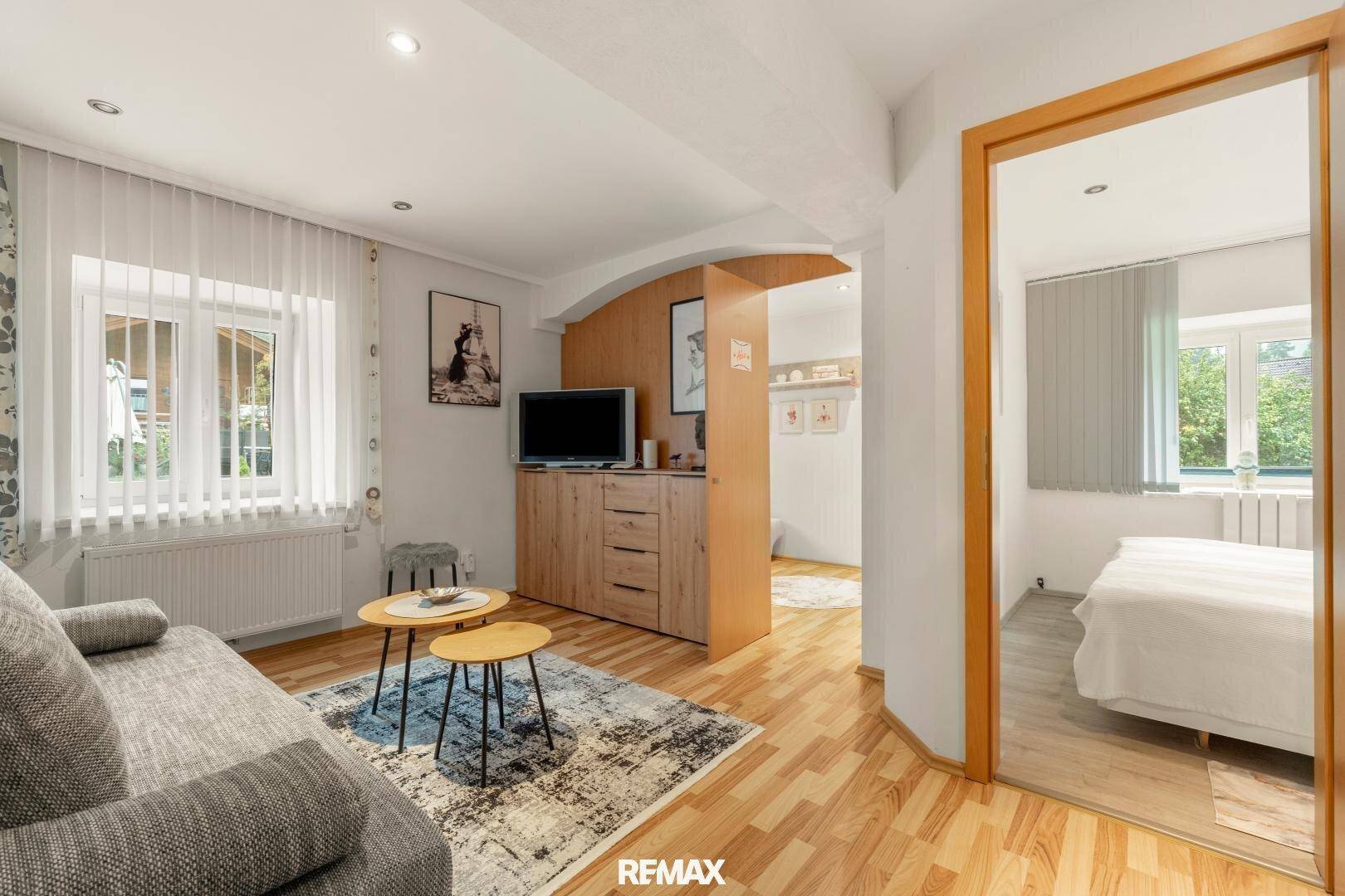 Gemütlicher Wohnbereich mit Sofa, Couchtischen und TV-Möbeln, offen zu einem weiteren Raum.