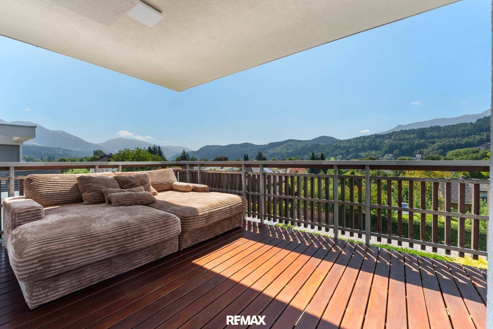 Großer Balkon mit Holzboden und bequemen Liegemöbeln, ideal zum Entspannen.