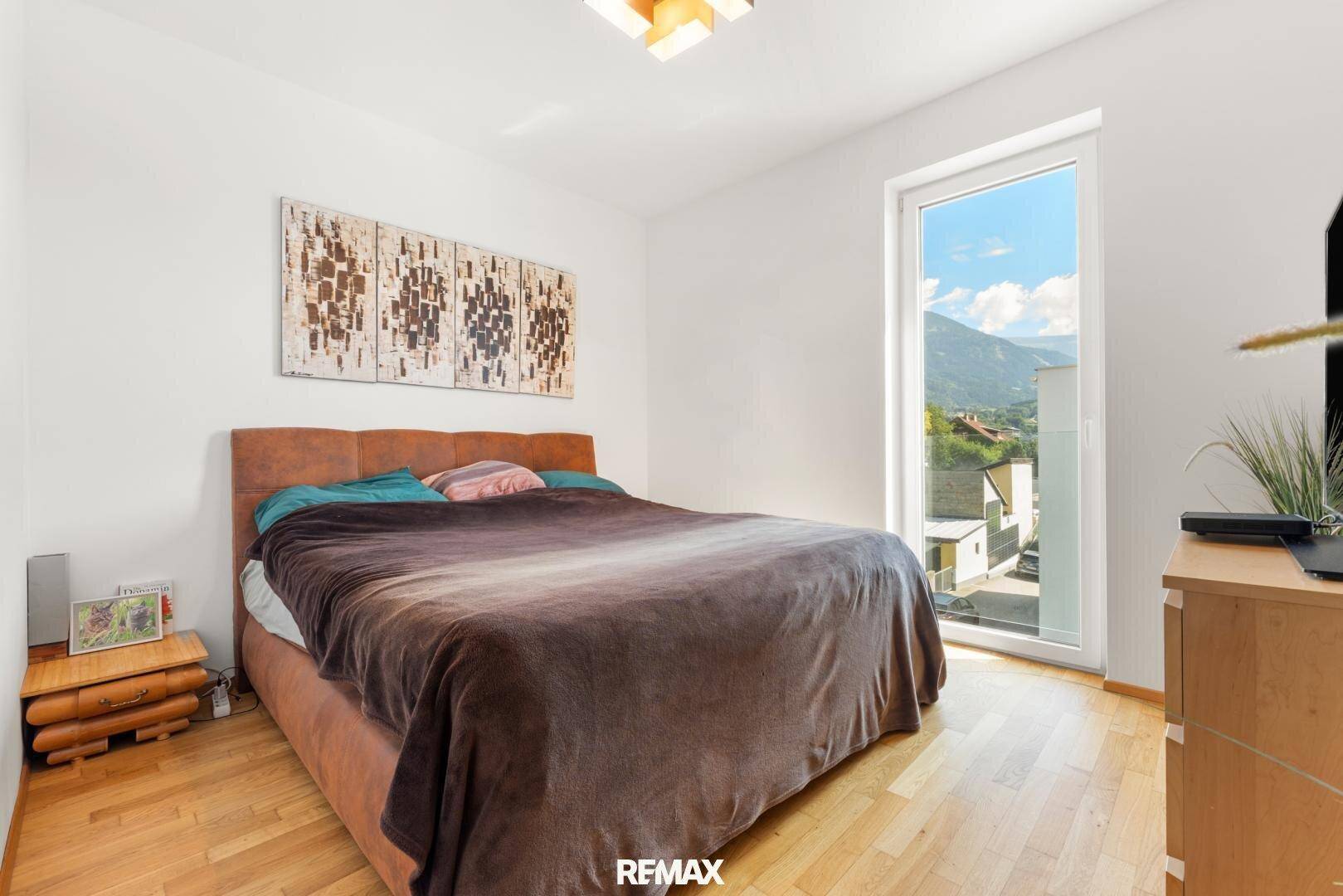 Gemütliches Schlafzimmer mit Holzboden, großem Bett und Fenster mit Bergblick.