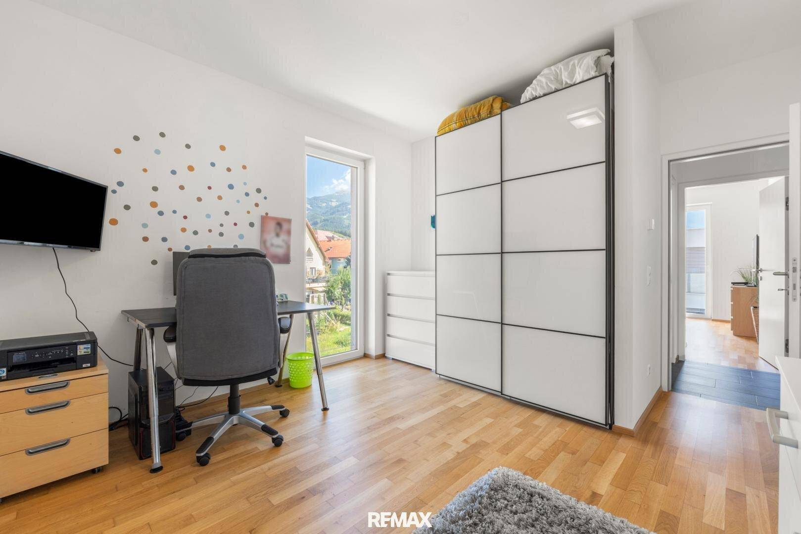 Helles Zimmer mit Holzboden, Schreibtisch und großem Kleiderschrank, ideal als Kinder- oder Arbeitszimmer.