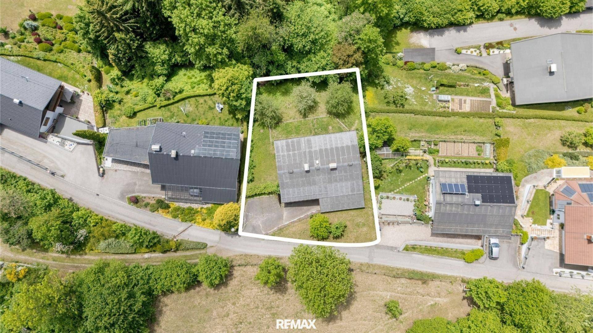 Luftaufnahme des Grundstücks mit Haus, Garten und umliegender Bebauung in grüner Umgebung.