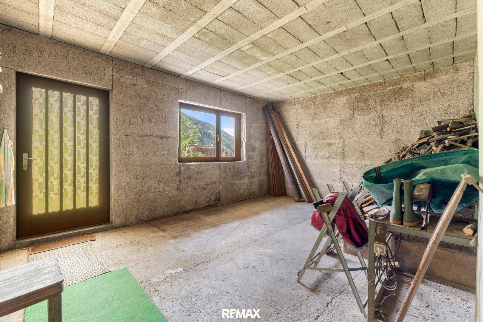 Unausgebauter Kellerraum mit Betonboden, Fenster und Lagerfläche.