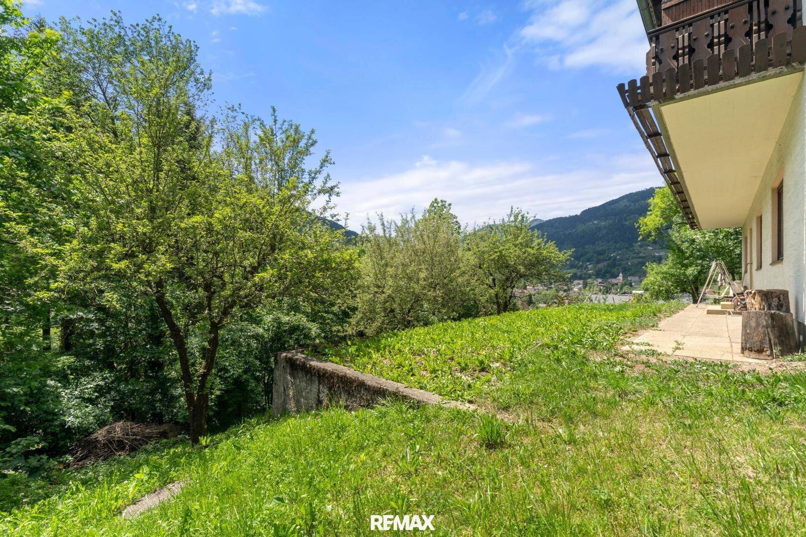 Grüner Gartenbereich neben dem Haus mit Blick auf die umliegende Berglandschaft.