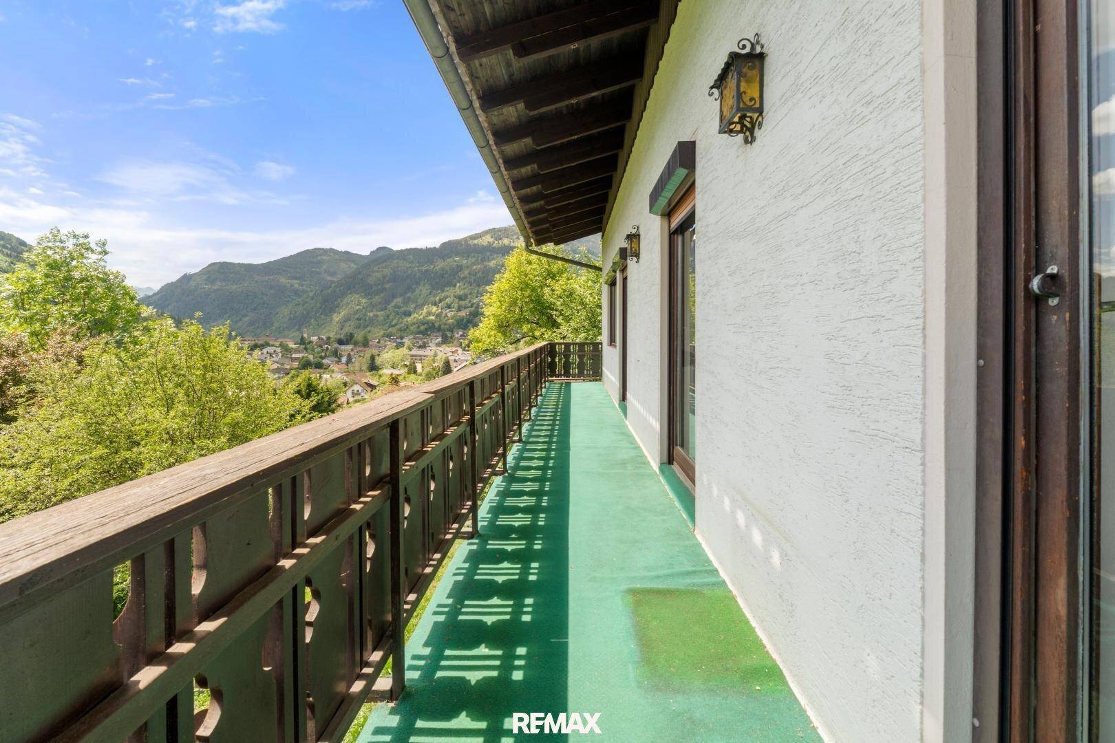 Langer Balkon mit traditionellem Holzgeländer und weitem Blick über das Tal und die Berge.