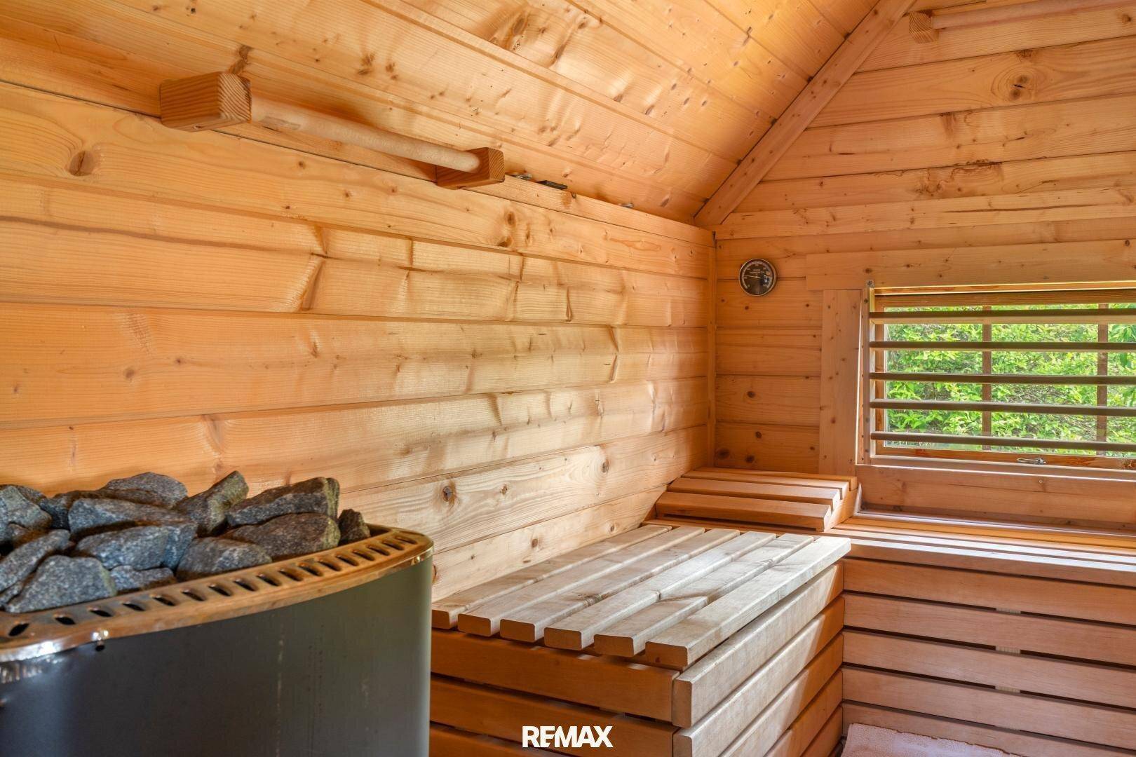 Gemütliche Holzsauna mit traditionellem Ofen und einem kleinen Fenster, das Licht hereinlässt.