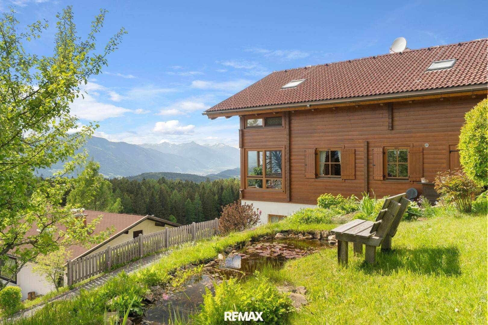 Idyllischer Gartenbereich mit kleinem Teich, Holzbank und weitem Bergblick.