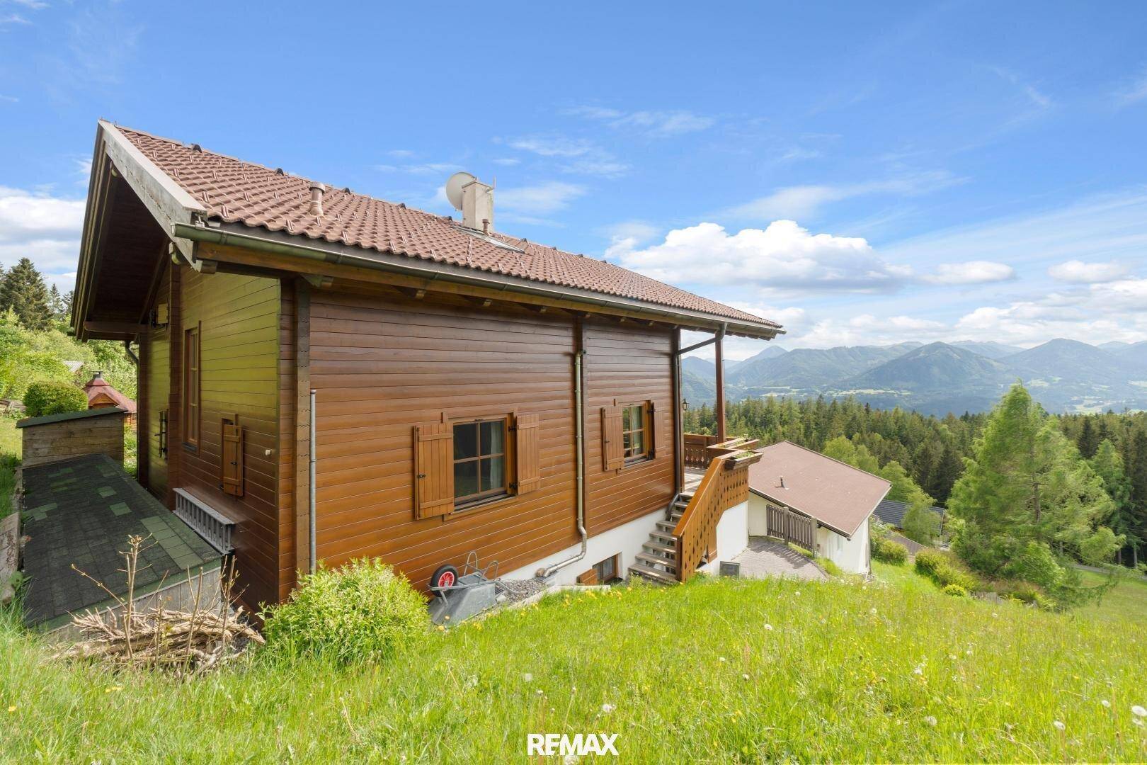 Seitenansicht des Holzhauses mit traditioneller Architektur und grüner Umgebung.