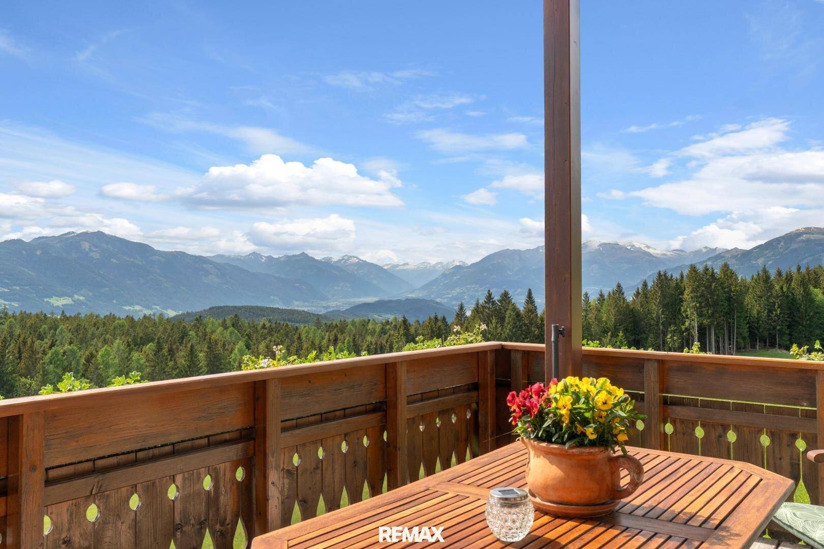 Geräumiger Holzbalkon mit Esstisch und atemberaubendem Bergblick.