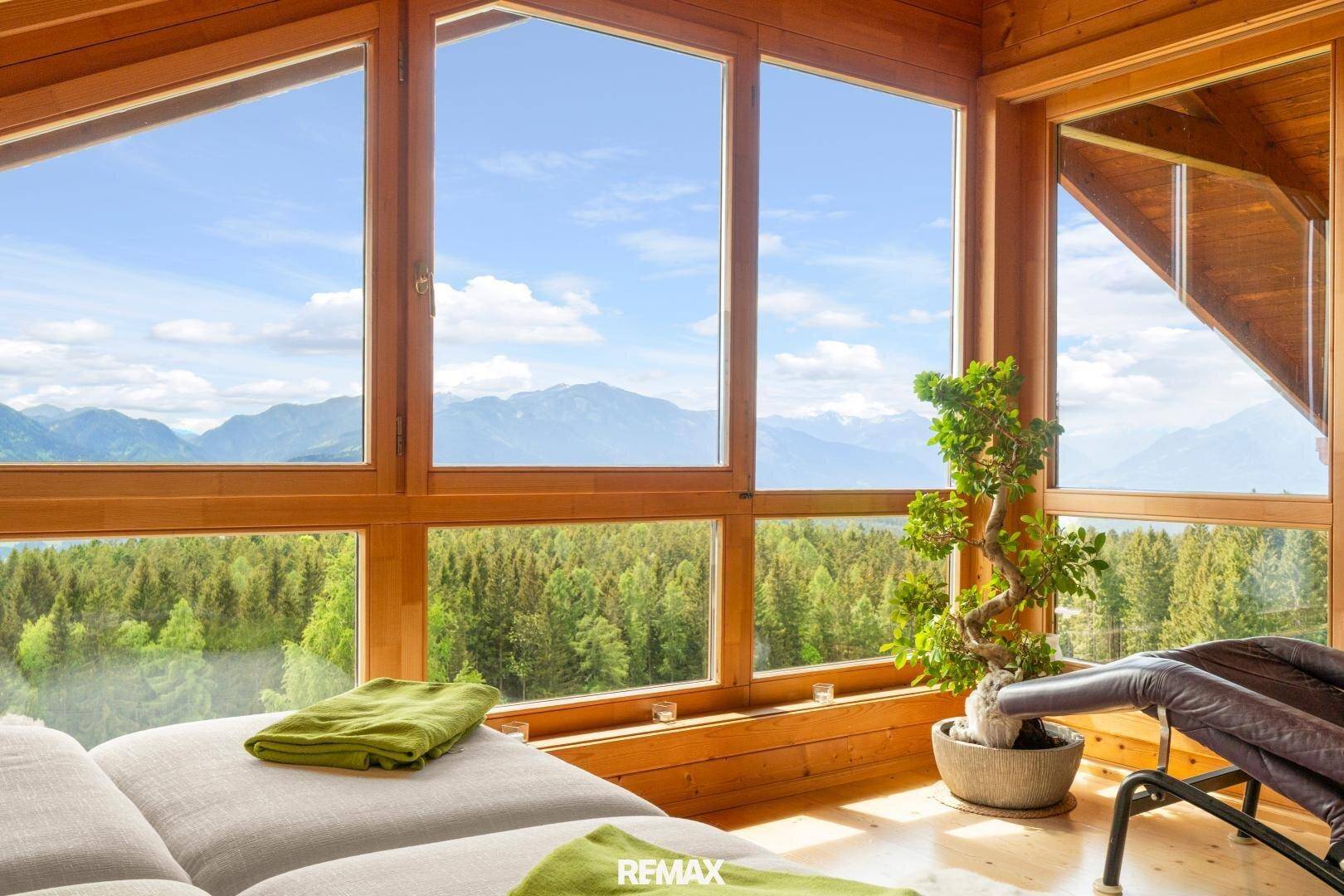 Entspannungsbereich mit großen Fenstern, die einen weiten Blick auf die Berge und Wälder bieten.