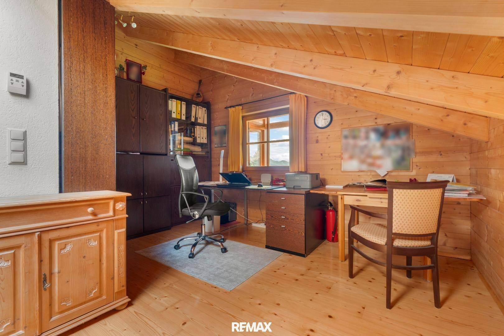 Helles Arbeitszimmer mit Holzwänden, Dachschräge und Blick ins Grüne.