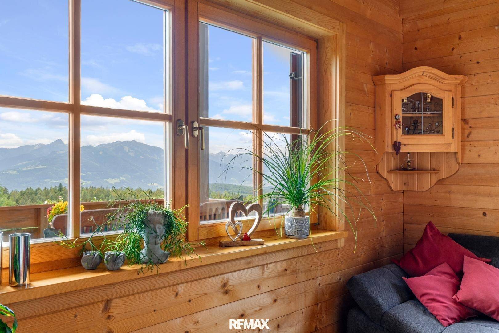 Gemütlicher Bereich mit Holzwänden, Dekoration und Fenster mit Bergblick.