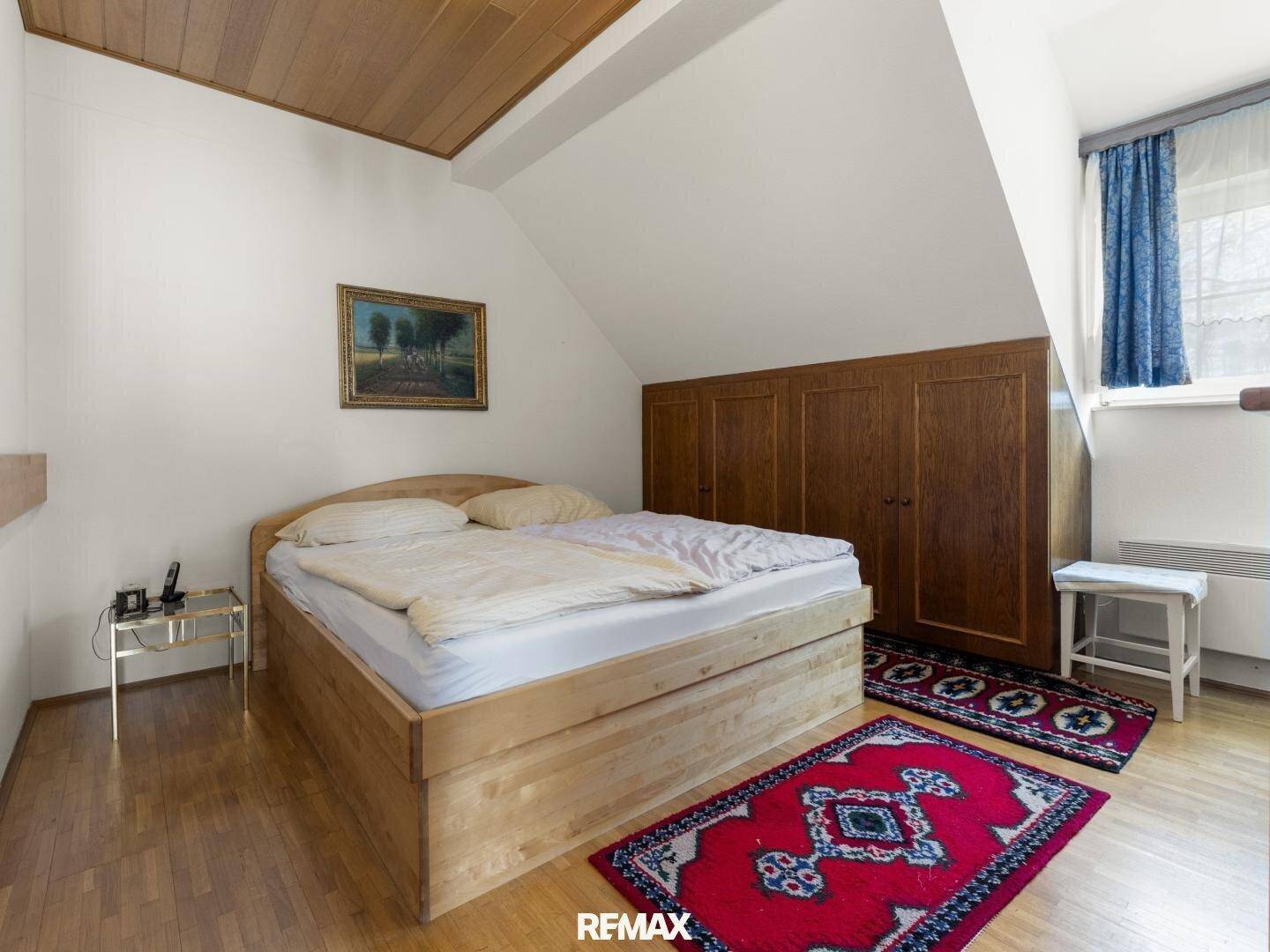 Schlafzimmer mit Holzdecke, Doppelbett und Einbauschränken unter der Dachschräge.
