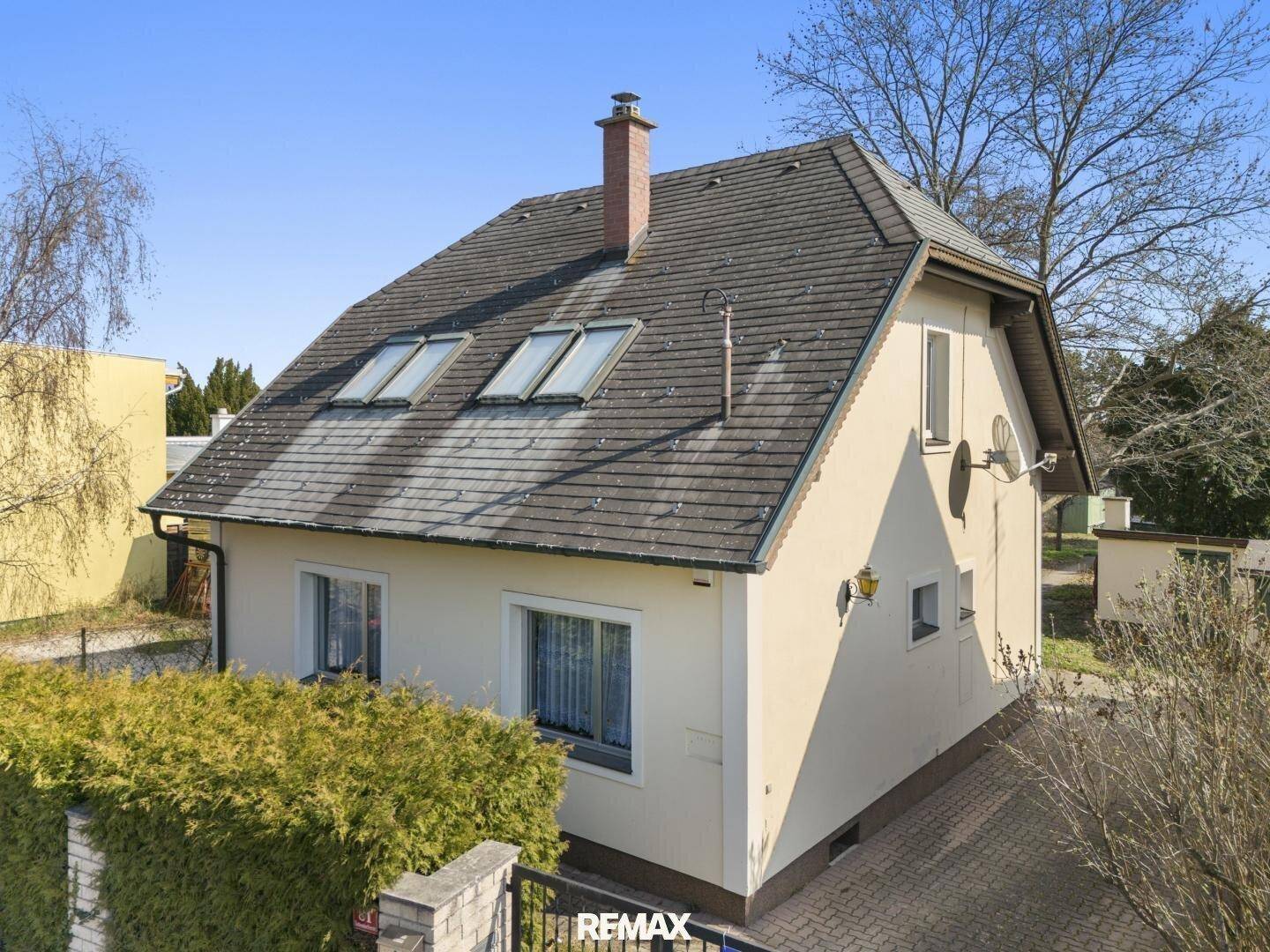 Rückansicht des Hauses mit Dachfenstern und Schornstein, umgeben von einem gepflegten Gartenbereich.