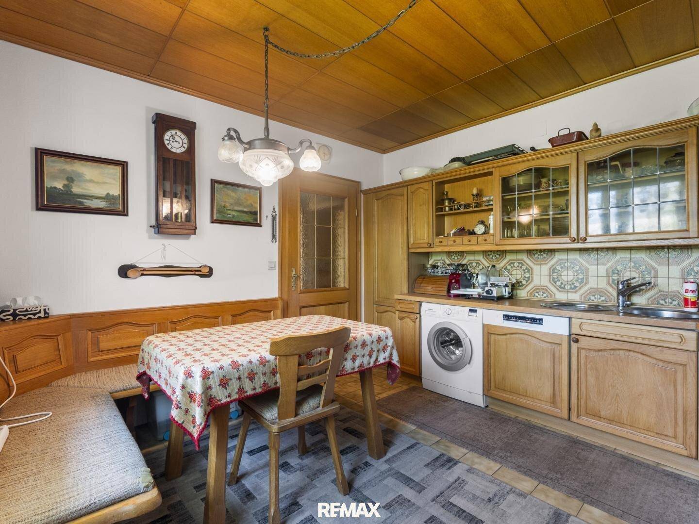 Gemütliche Küche mit Holzeinrichtung, Waschmaschine und traditionellen Fliesen an der Wand.